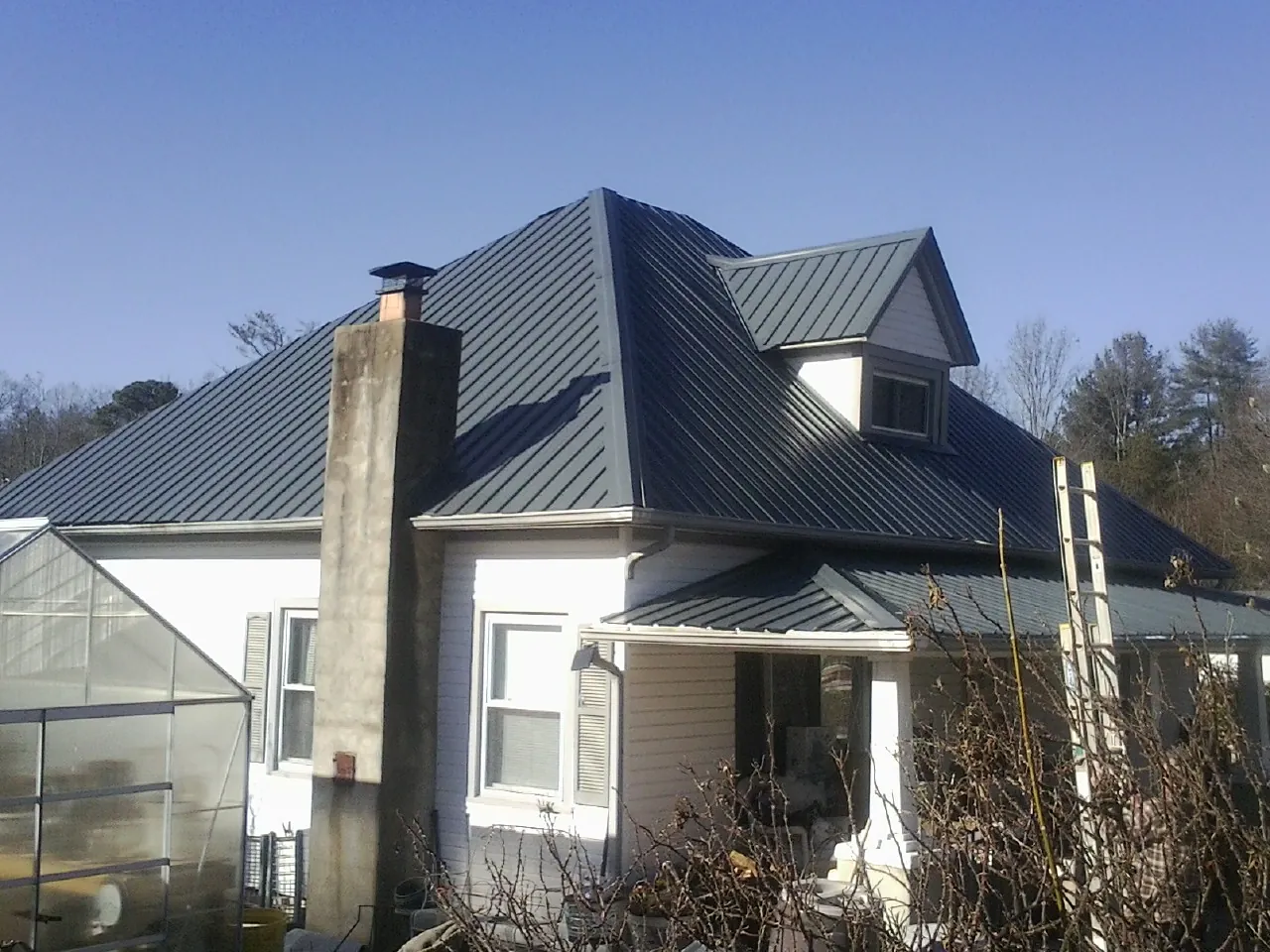 Dark blue standing seam metal roof on a white farmhouse with dormer — Slate & Tile Roof Repair by Roofing Brothers in Yellow Springs