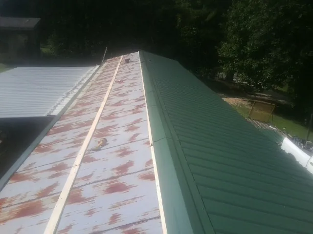 Old rusted panels beside newly installed green metal roofing — Wind Damage Roof Repair by Roofing Brothers in Yellow Springs