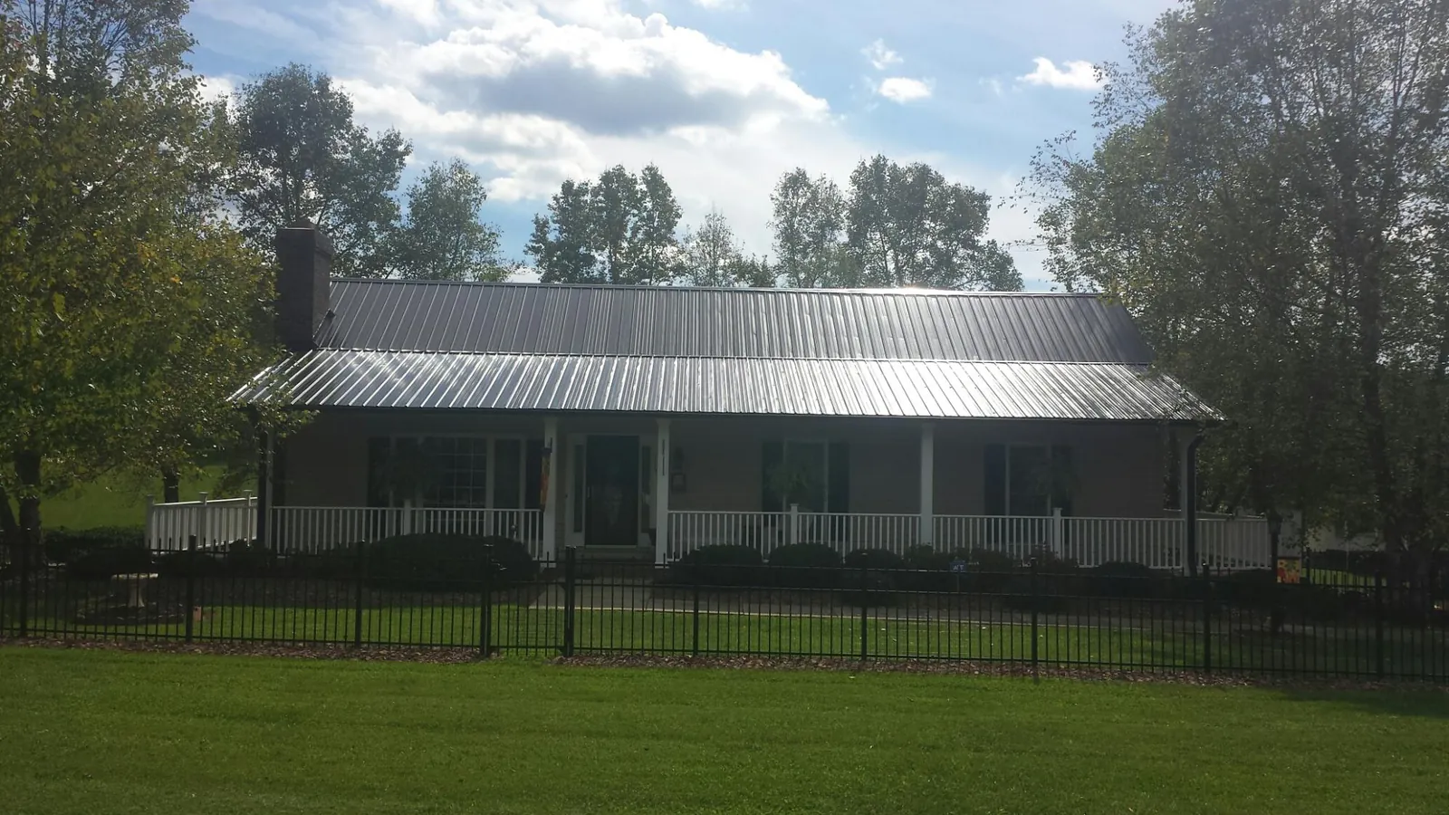 Gray metal roof on a brick ranch with a full width front porch — Gutter Guard Installation work by our crew in Yellow Springs