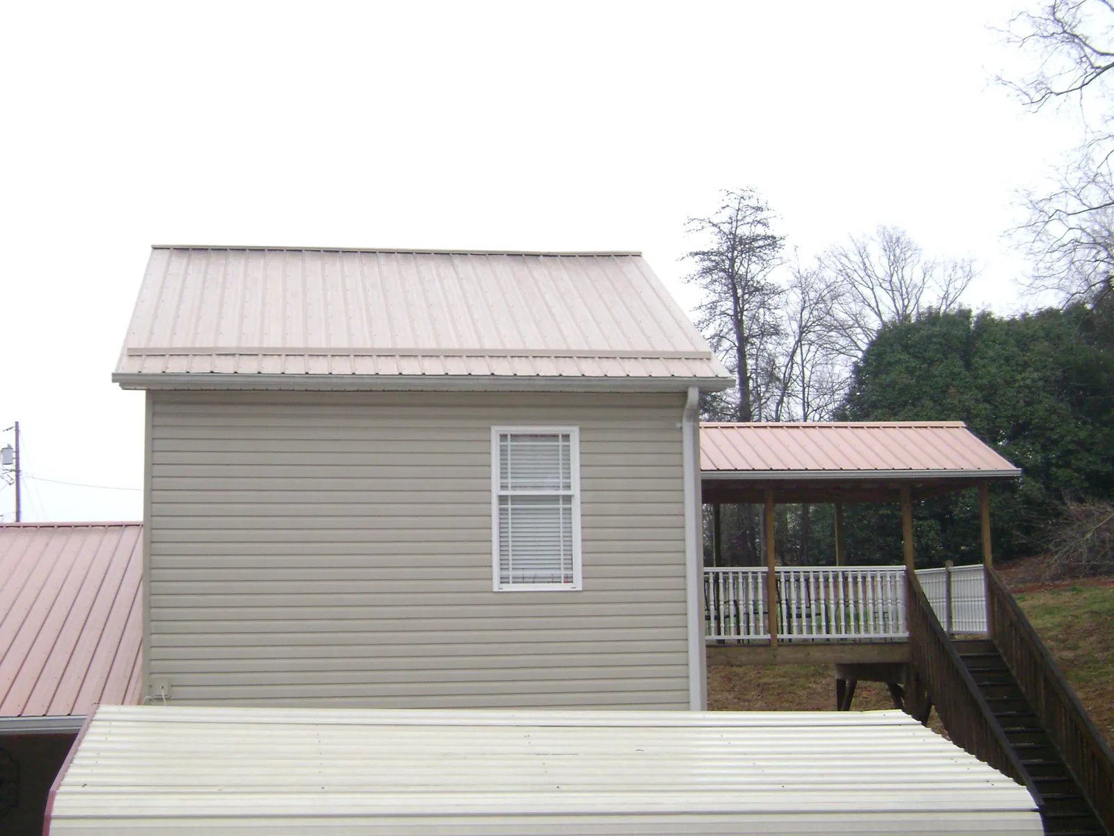 Tan metal roofs on a two story addition and attached porch, from a Roof Replacement job in Yellow Springs