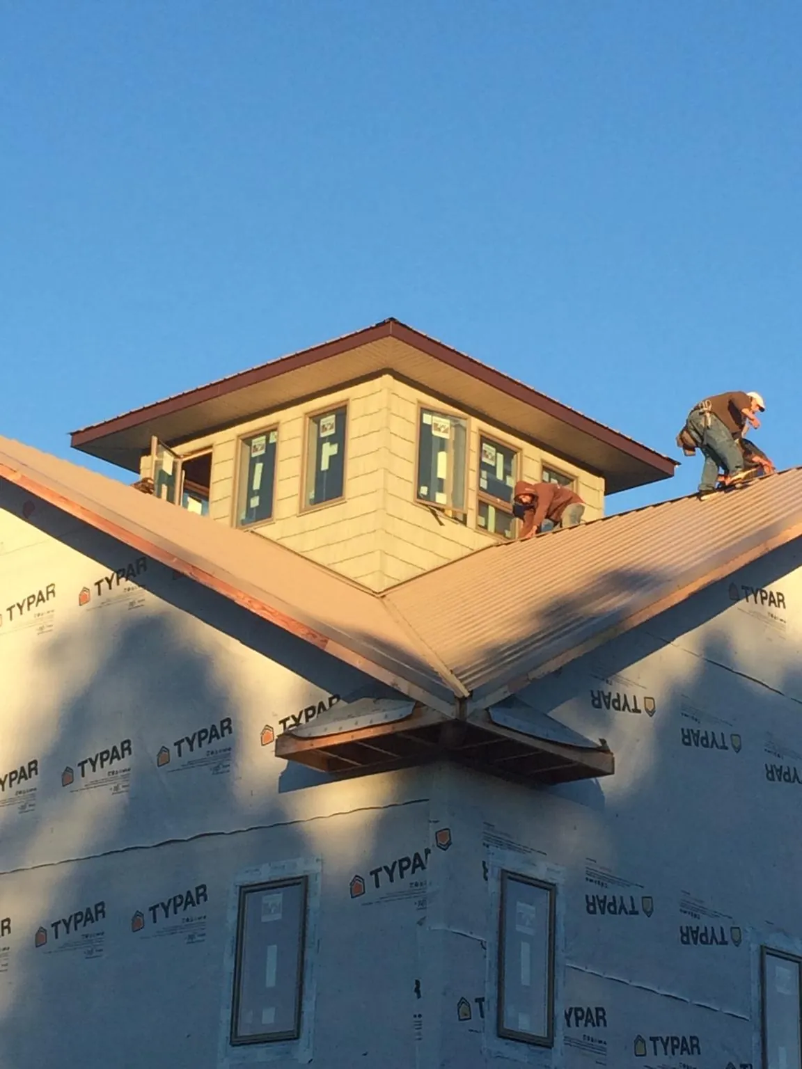 Roofers working around a rooftop cupola on a new metal roof at sunset — Roof Waterproofing in Yellow Springs by Roofing Brothers